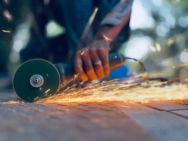 A cut-off wheel on an angle grinder cutting steel, throwing sparks