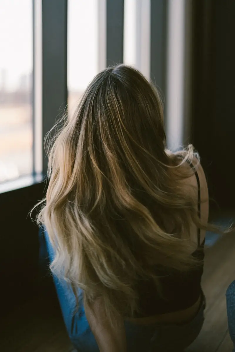 Long, wavy, sun-lit brown and blonde hair, seen from behind